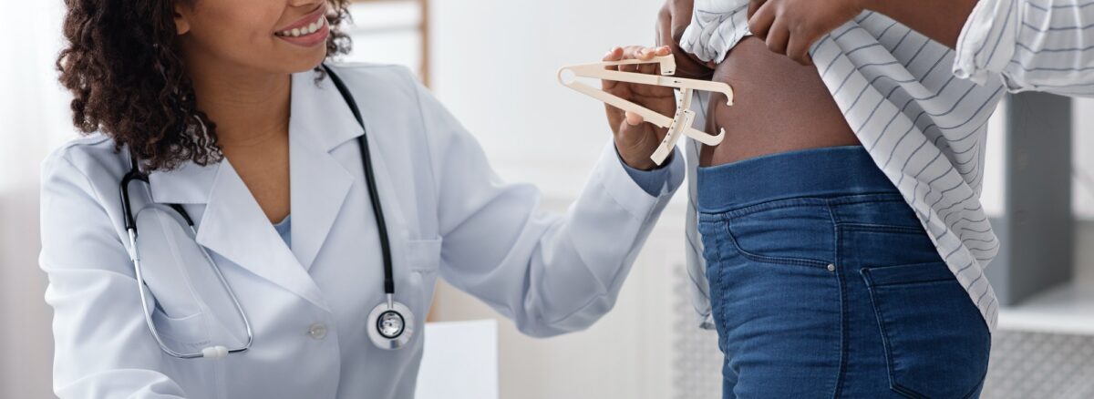 Doctor checking patient body fat index with caliper